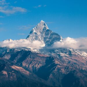 Breathtaking view of a snow-covered mountain peak surrounded by clouds during sunrise.
